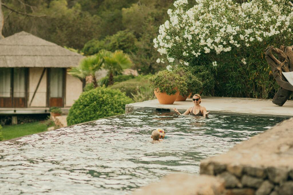 Swimming pool and Mediterranean garden at Villa Paradiso in Ibiza, with guests enjoying the water.