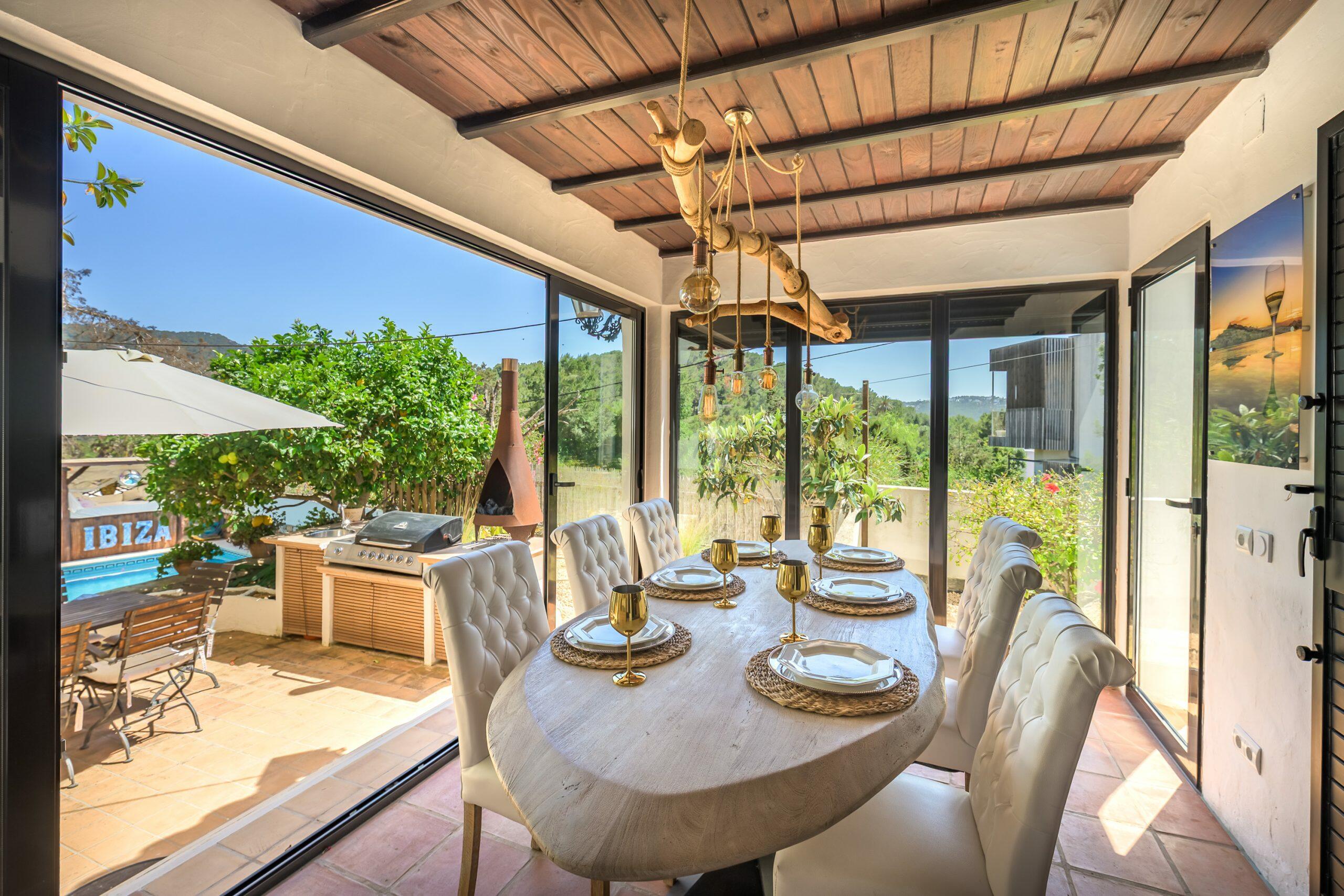 Inge-SaleCalaLlonga(15) Dining area opening onto the terrace, pool and garden at an Ibiza home.