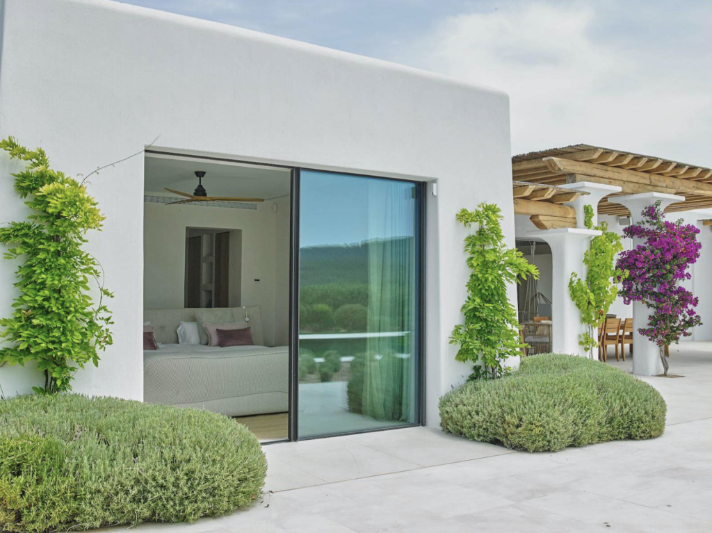Blakstad villa in Ibiza with whitewashed walls, sliding glass doors, landscaped garden and covered terrace.